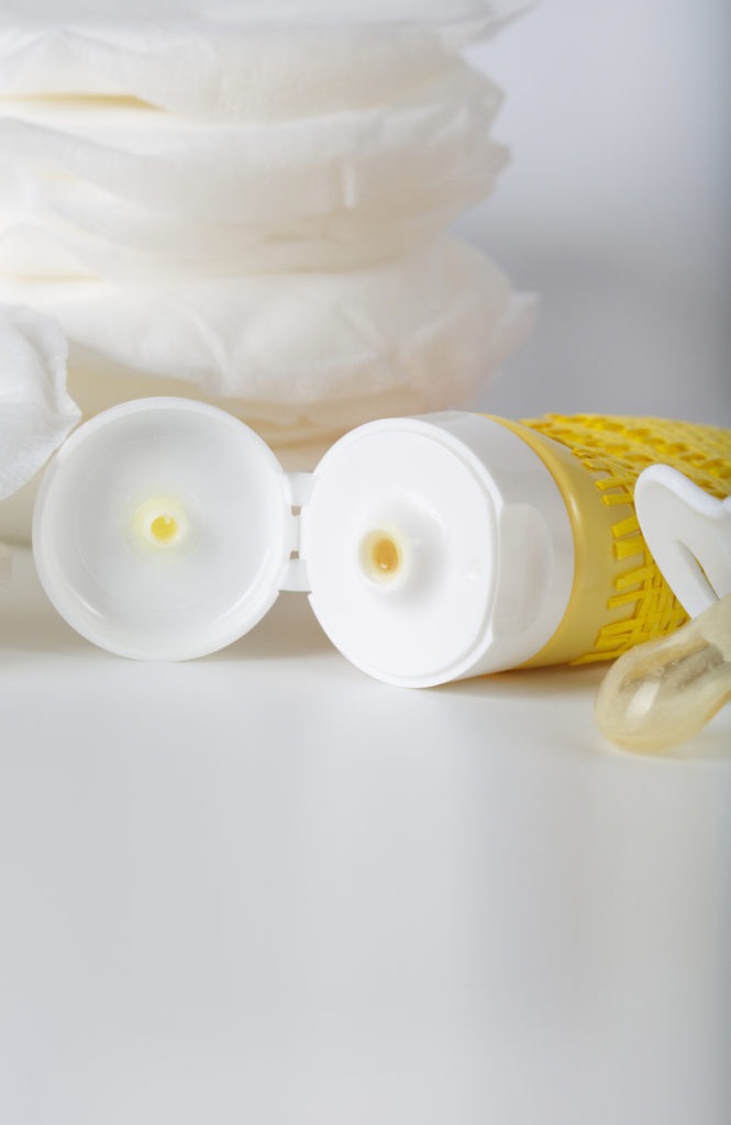 tube of lanolin cream, breast pads, pacifier in white background