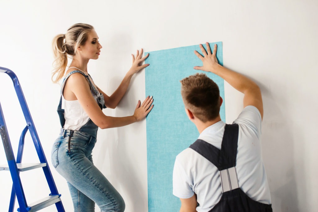 woman and her husband wallpapering the walls
