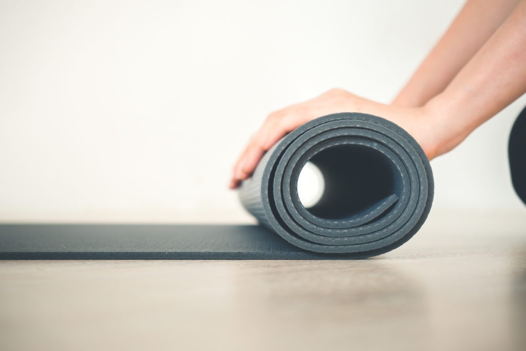 close up woman hand rolling yoga mat in yoga class work out