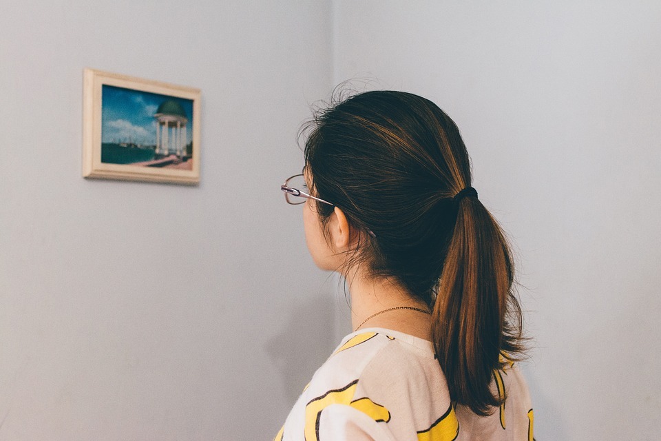 woman-looking-at-a-picture-frame-on-the-wall