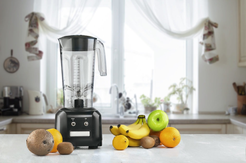 A countertop blender and fruits on a kitchen space
