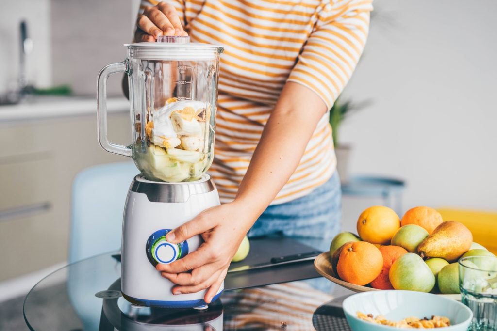 A woman preparing smoothie using commercial blender
