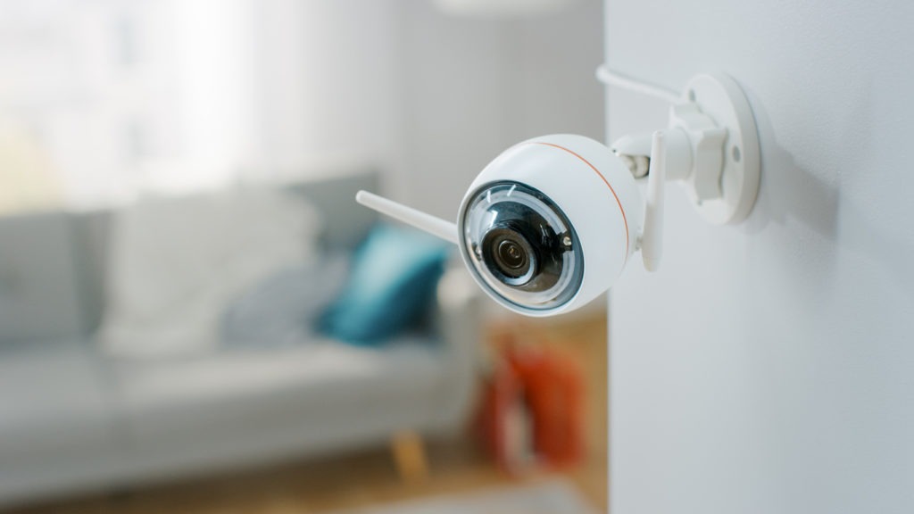 Close Up Object Shot of a Modern Wi-Fi Surveillance Camera with Two Antennas on a White Wall in a Cozy Apartment