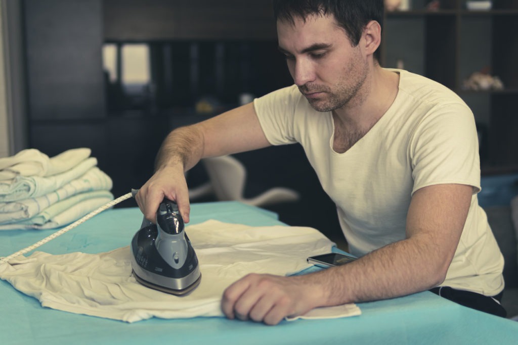 Man ironing clothes on table