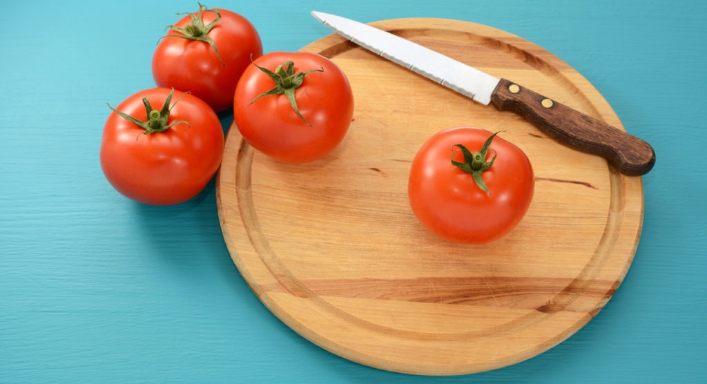 a tomato knife on a chopping board with fresh tomatoes