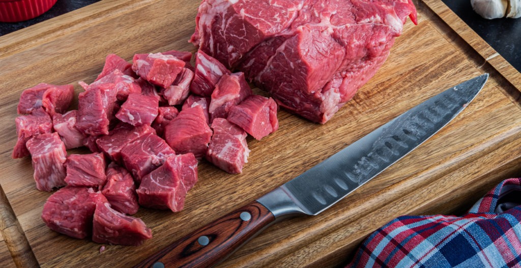 beef chunks next to a carving knife on a chopping board