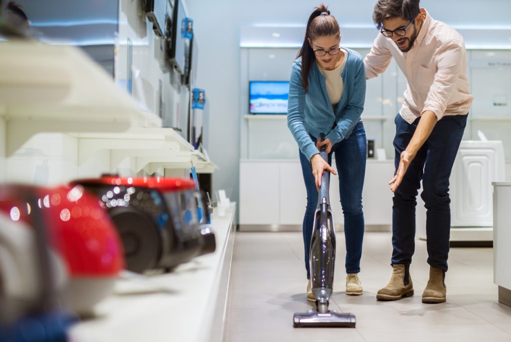 couple testing a vacuum cleaner at the store