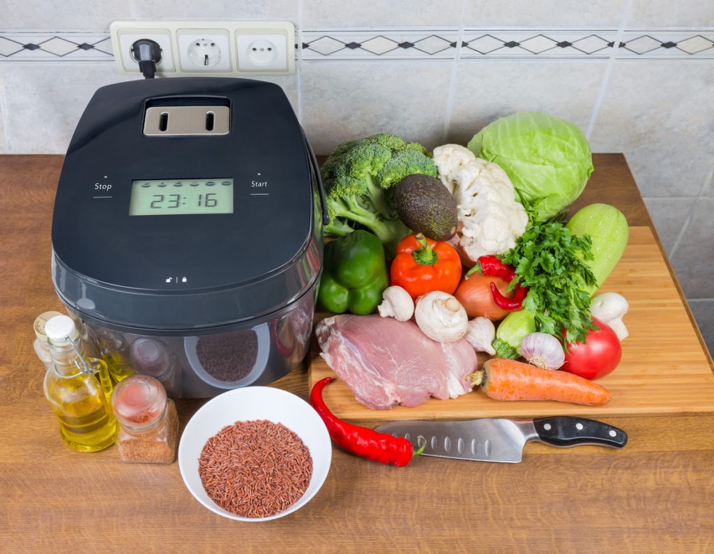 Electric multi-cooker among of raw foods on cook table