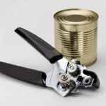 Food can and modern airtight can opener. Closeup, white background