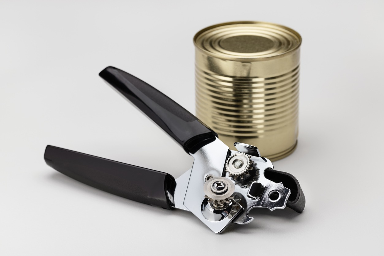 Food can and modern airtight can opener. Closeup, white background
