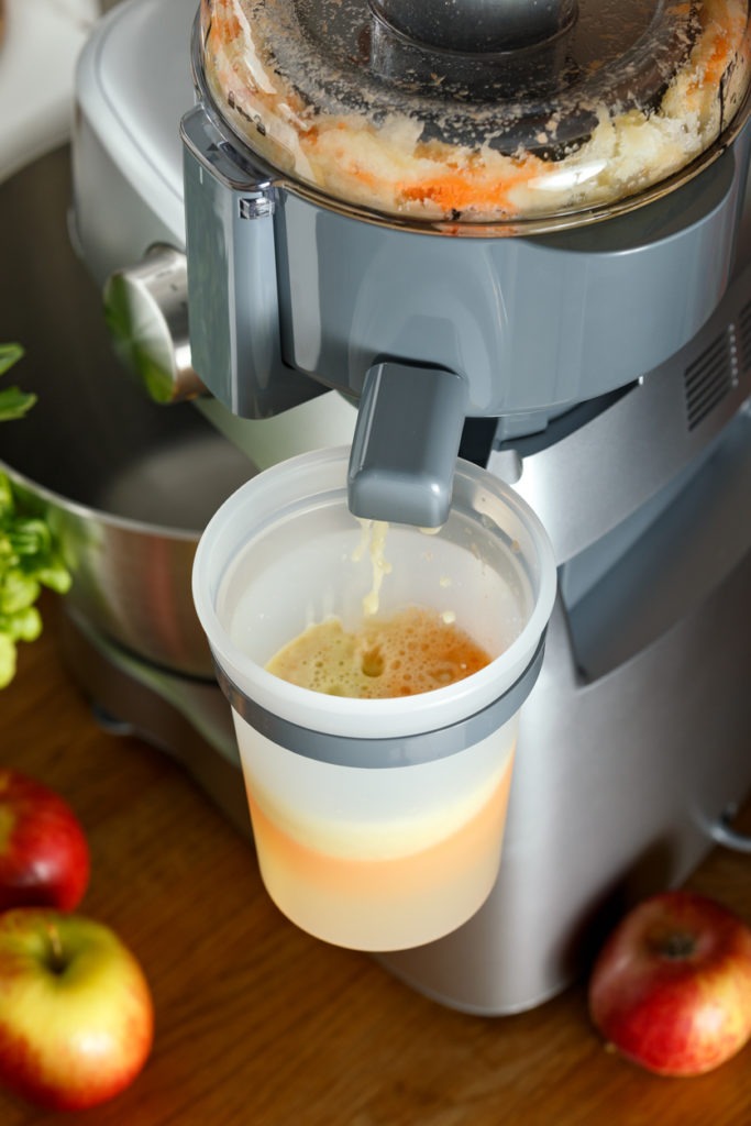 making fresh apple and carrot juice on kitchen centrifugal juicer, food processor