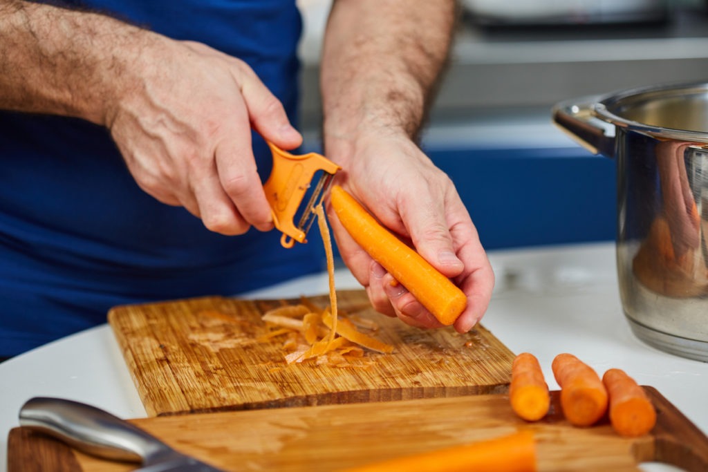 man peeling a carrot using a Y peeler