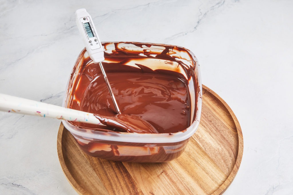 Melted chocolate is measured with thermometer to check the temperature before being poured into the mold