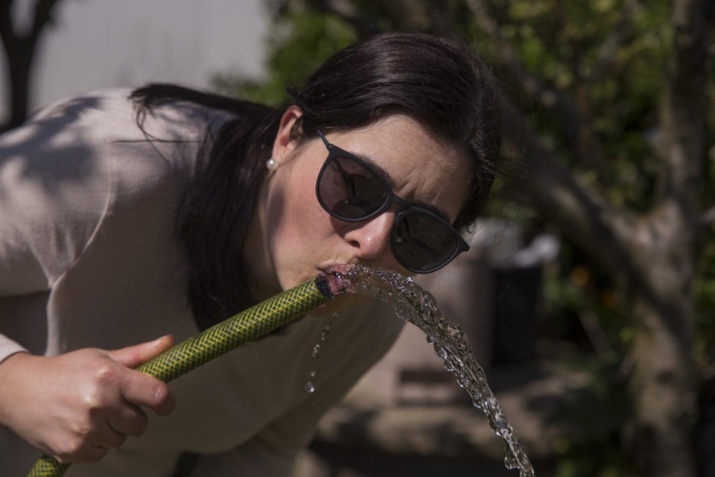 woman drinking water from a hose