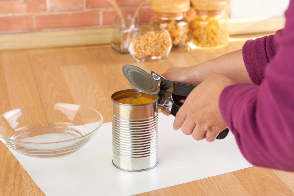 woman opening a can of corn with can opener