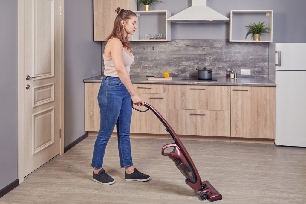 woman using an upright vacuum cleaner