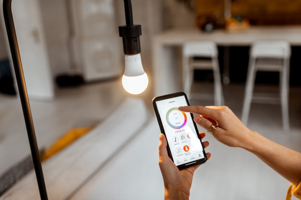 A person controlling light bulb temperature and intensity with a smartphone application.