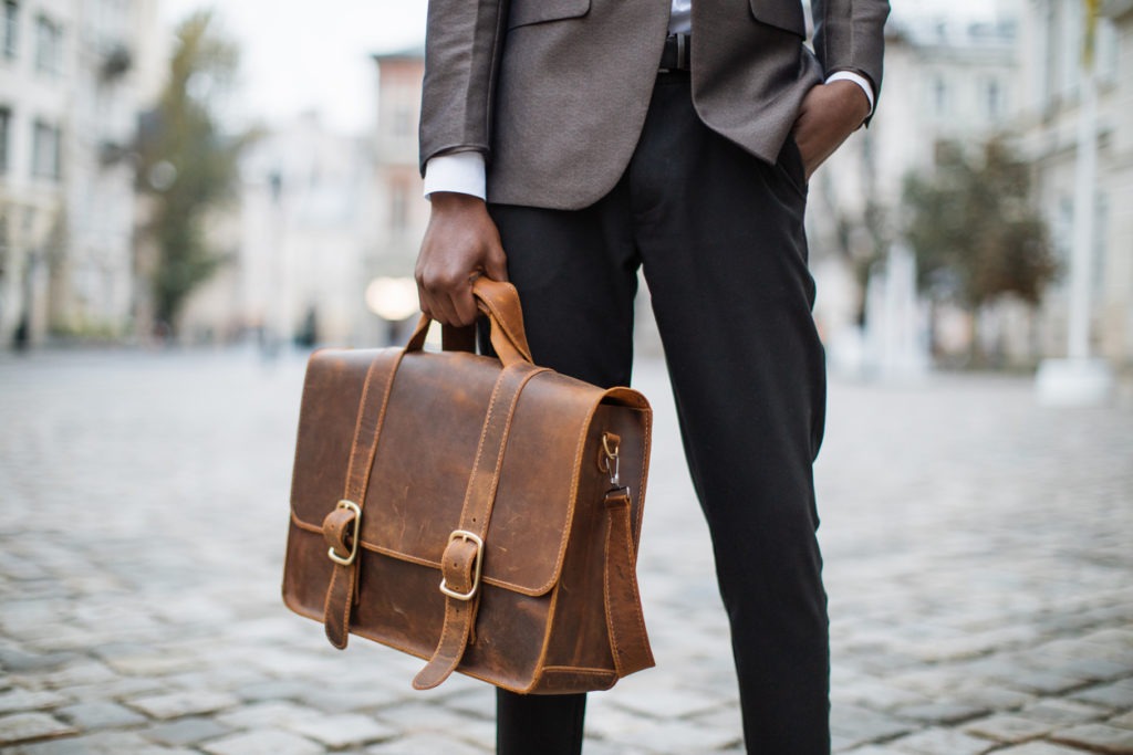 Close up of man carrying a brown briefcase.