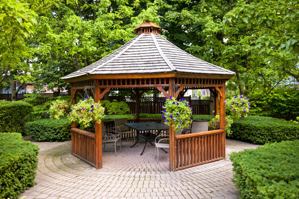 Gazebo with dining table in a garden.