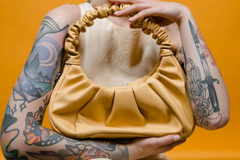 a person holding a beige leather handbag
