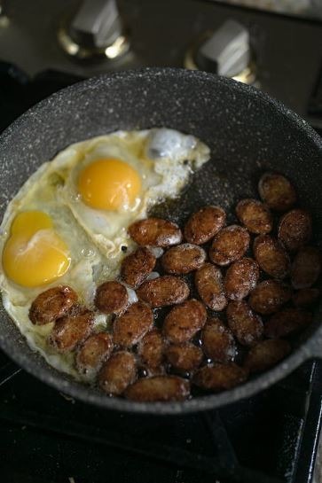eggs and sausages cooking on a non-stick pan