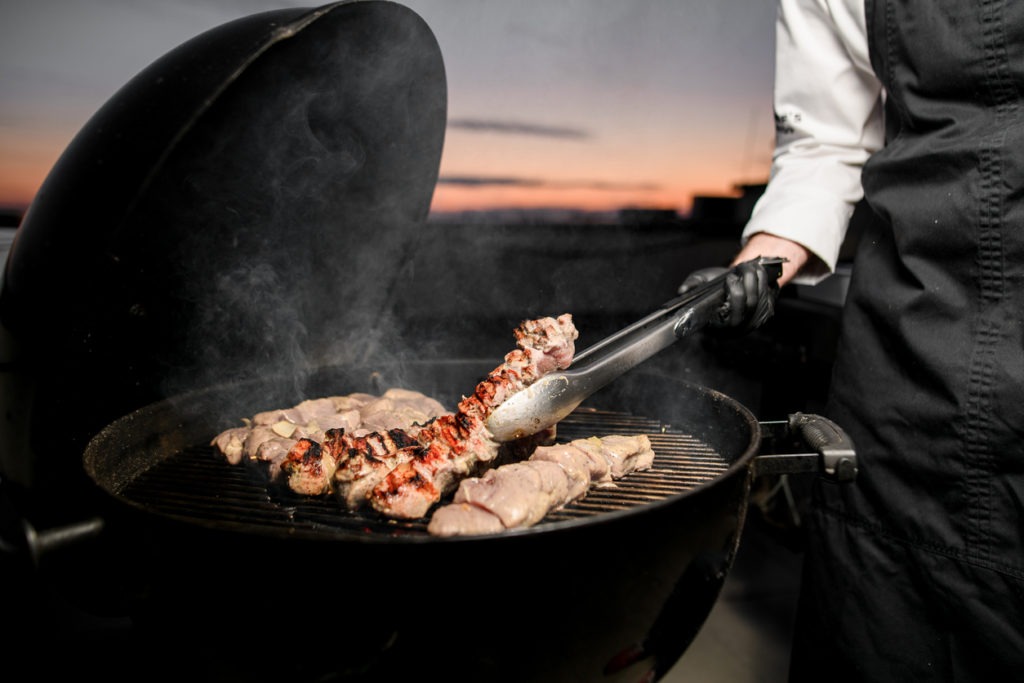 male cook gently turns meat on the grill