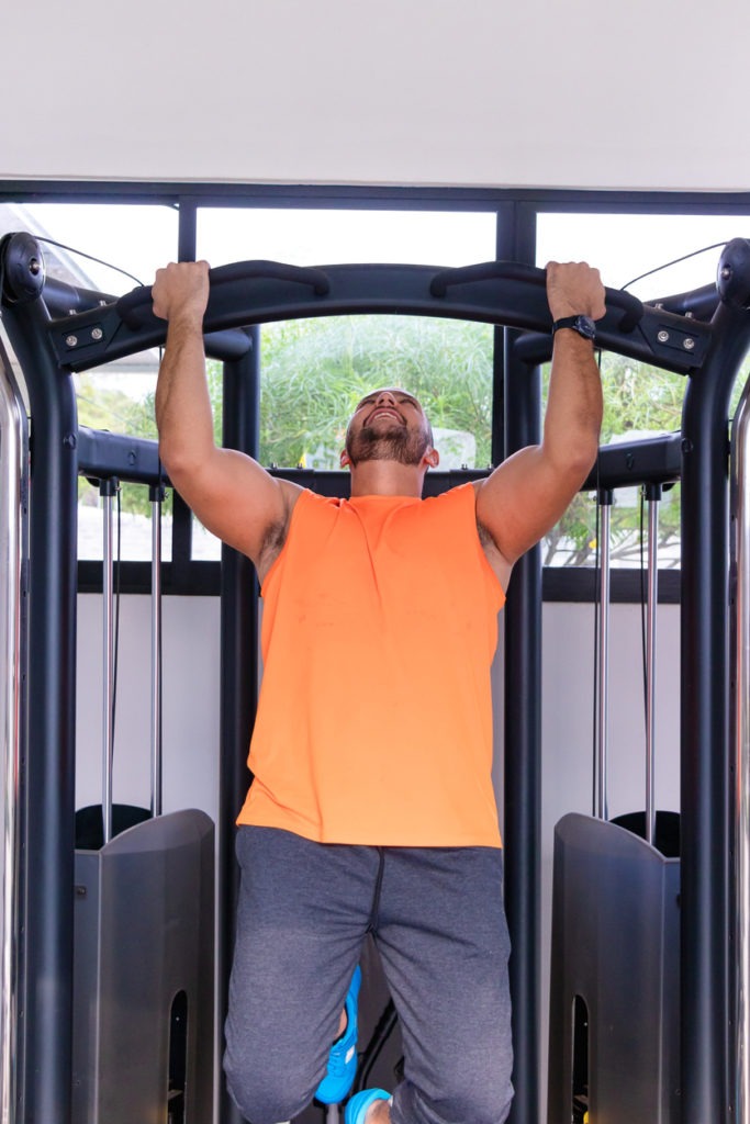 Young man doing pull-ups on stationary exercise machine