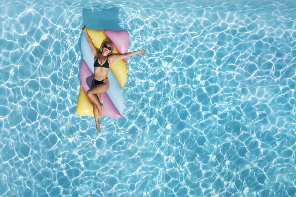Aerial top down view of a woman in bikini on a colorful float