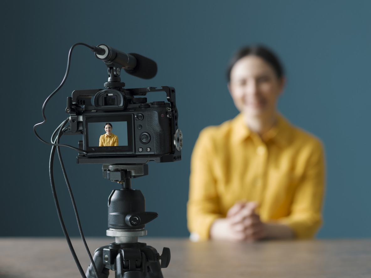 Smiling woman sitting in front of a camera and making a video blog