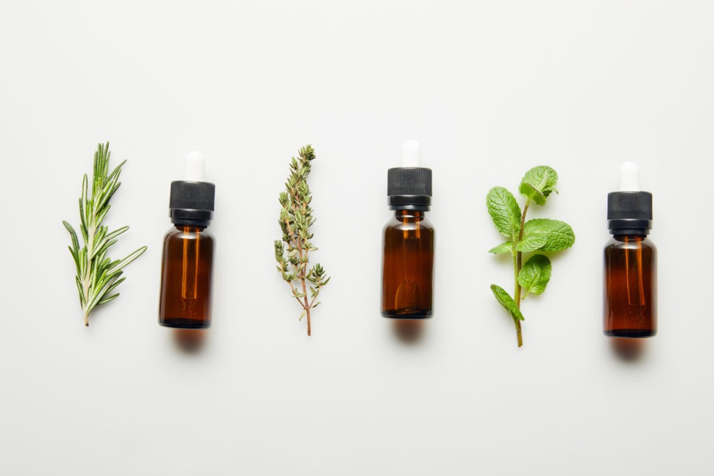 Flat lay with herbs and bottles with essential oil on white background