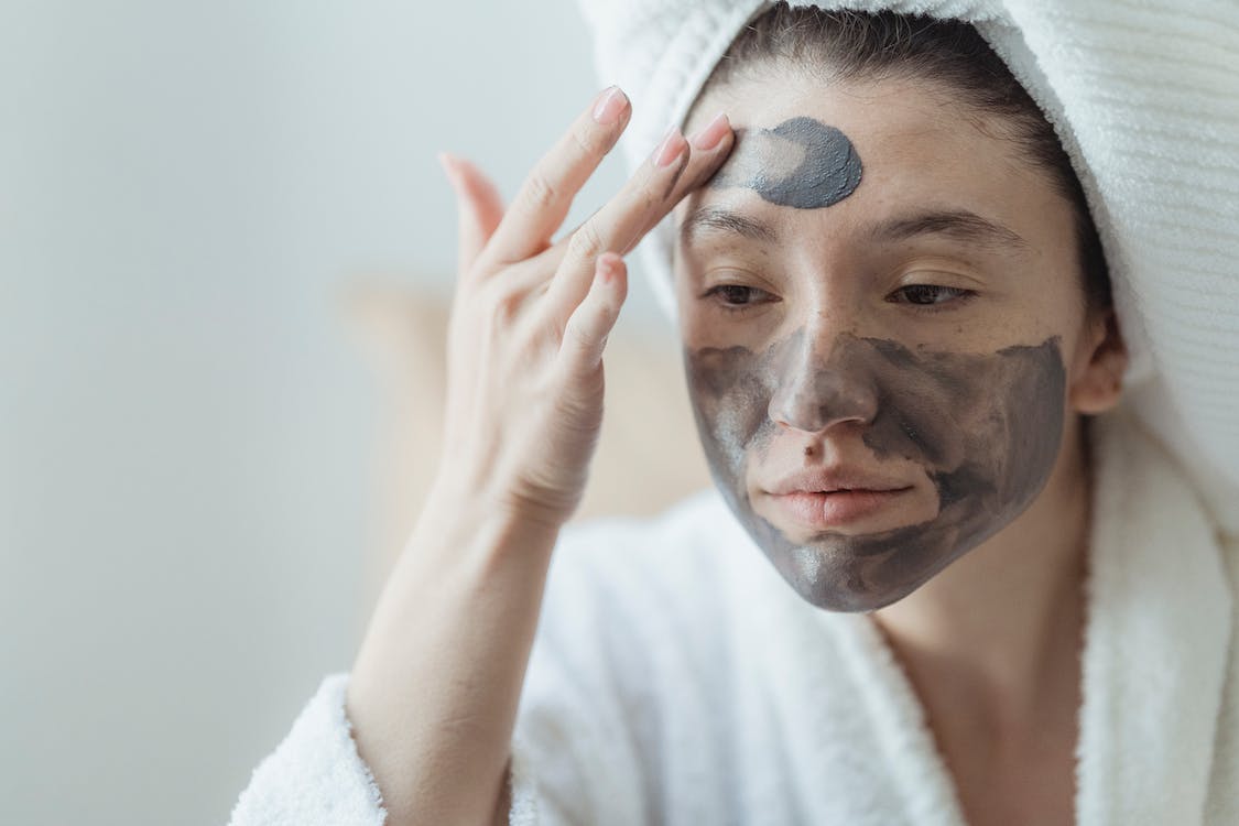 a woman in a robe applying a mud mask