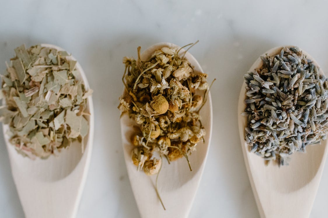 close up shot of herbal medicines on wooden spoons