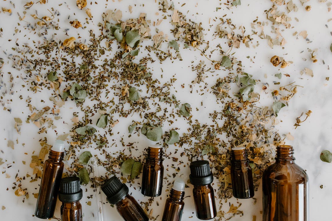 essential oil bottles and herbal medicine on white surface