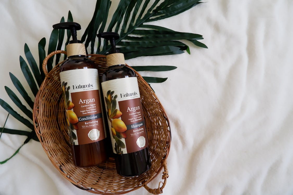two naturals argan oil bottle on a wooden basket
