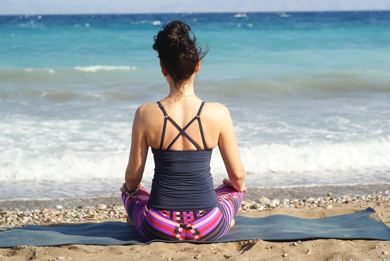 woman sitting on yoga matt at beach
