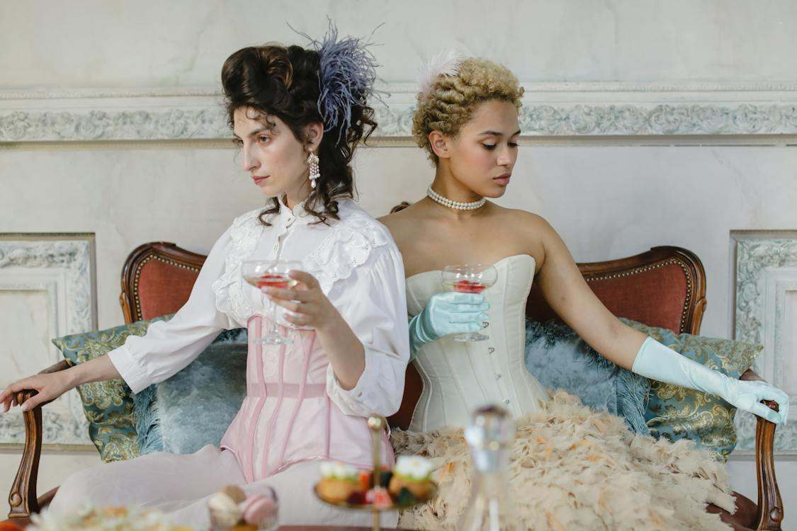2 women wearing tight corsets while sitting down