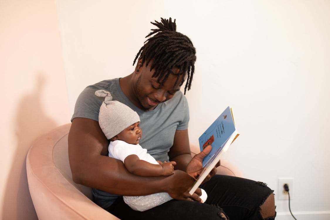 A Father Reading a Book to his Baby