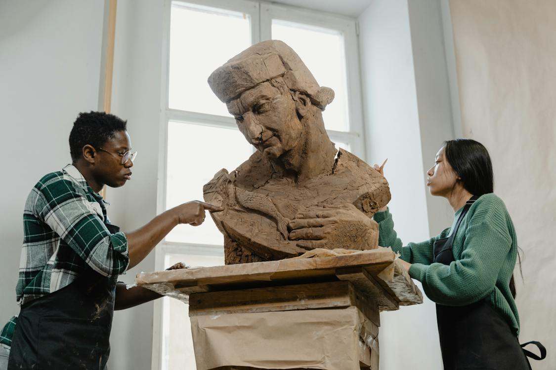 A man and woman sculpting a clay statue