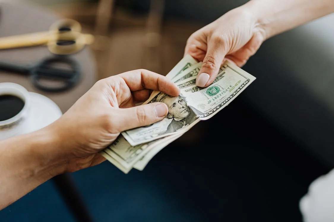 A man handing dollar bills to a woman