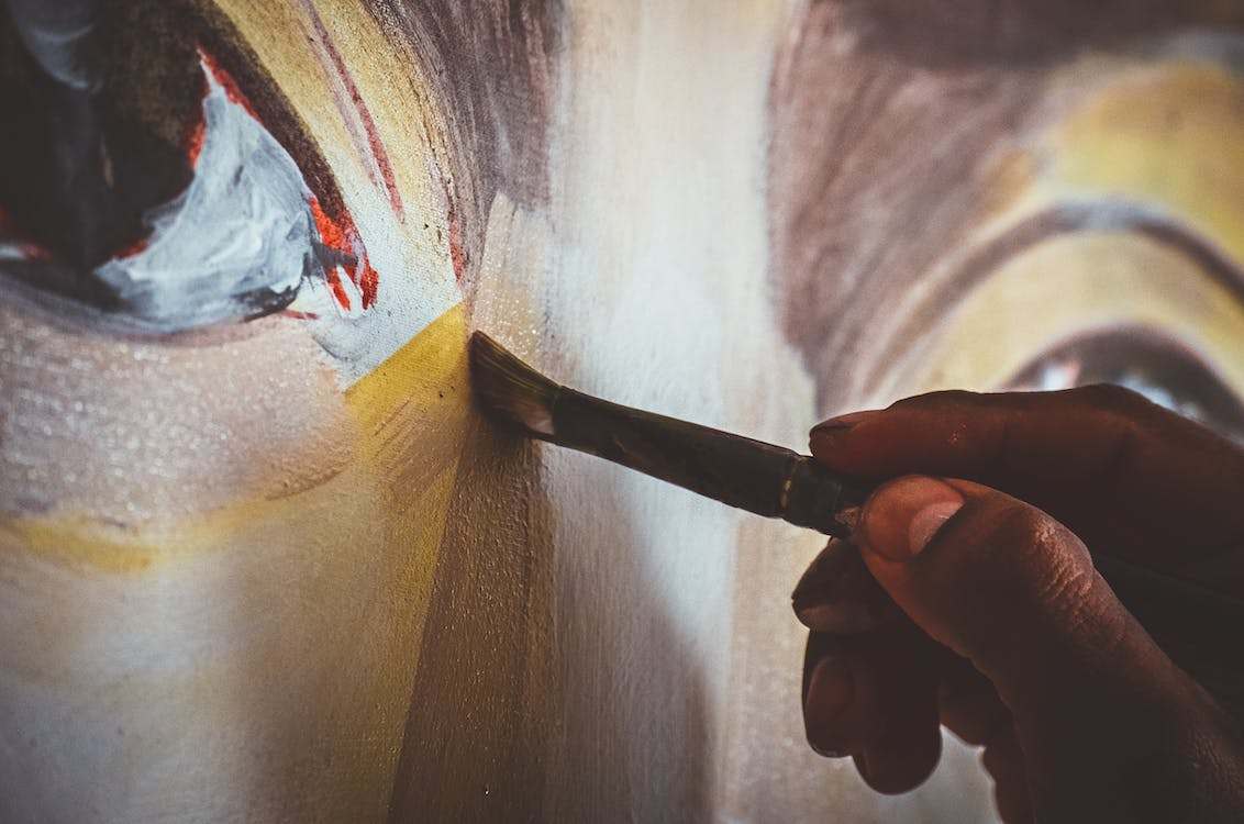 A man holding a paintbrush unto a canvas