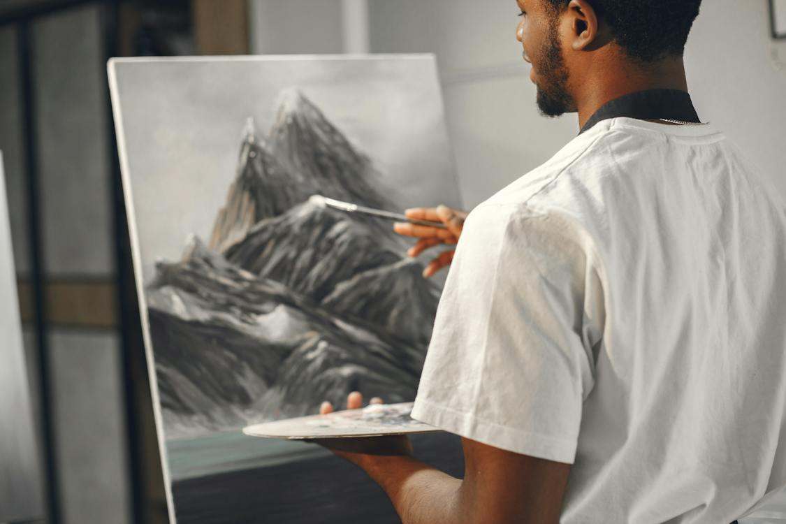 A man painting mountains on a canvas