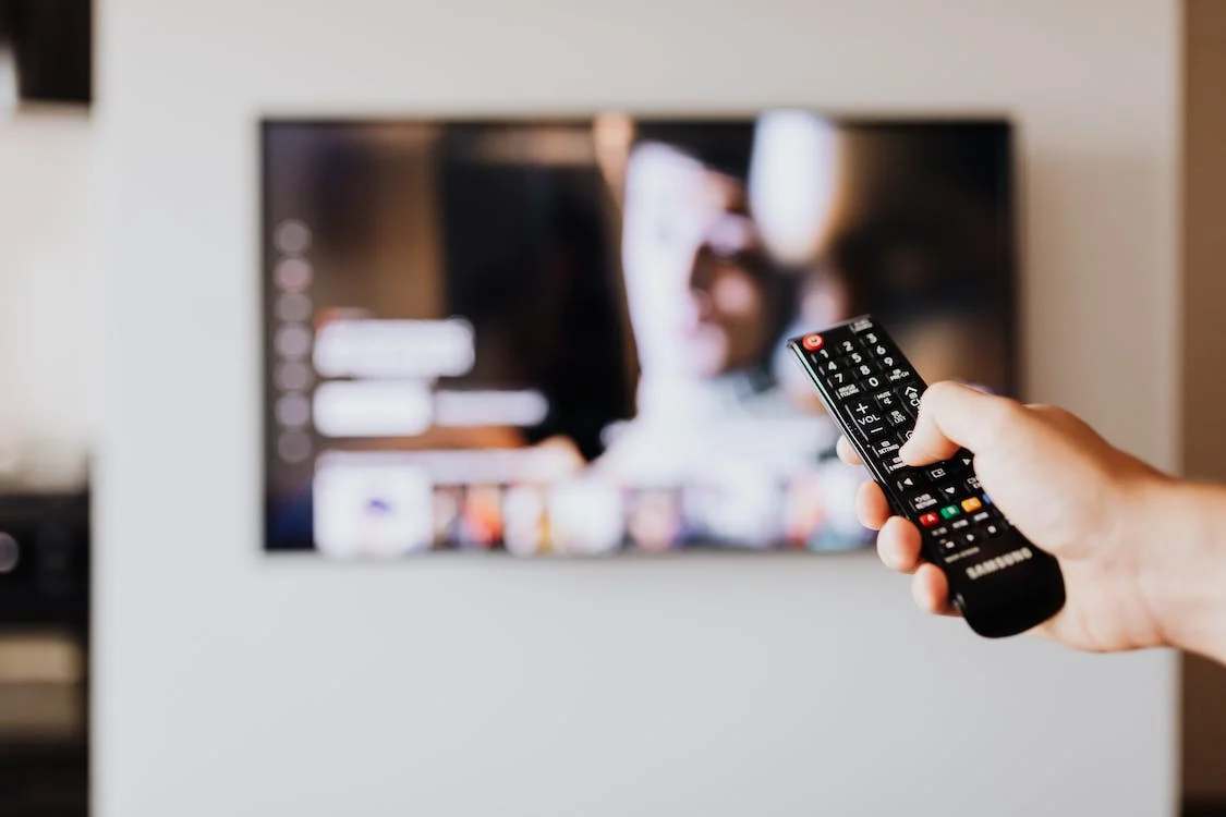 A person holding a remote towards a tv displaying Netflix