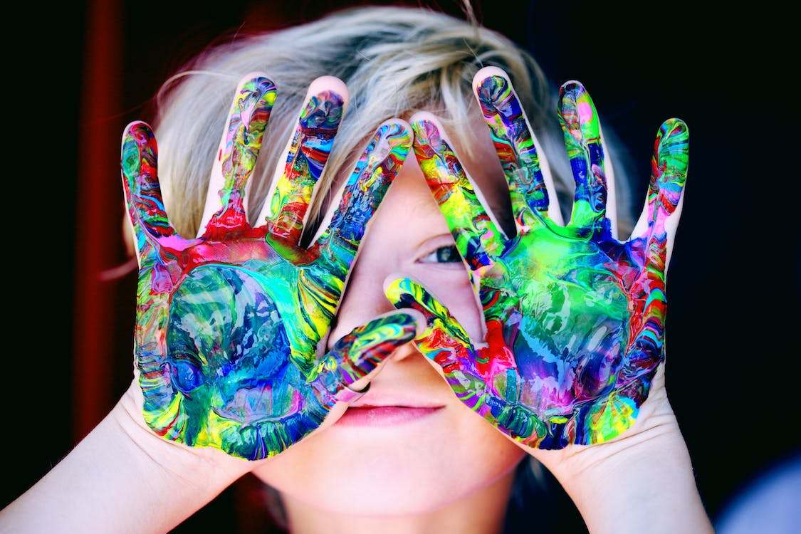 A photo of a kId with multi-colored hand paint