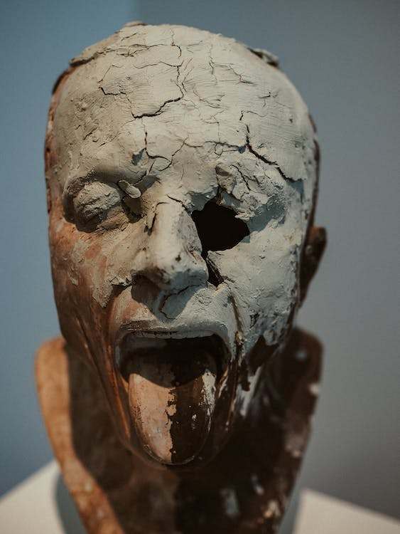 A ruined bust of a man with tongue out and a missing eye