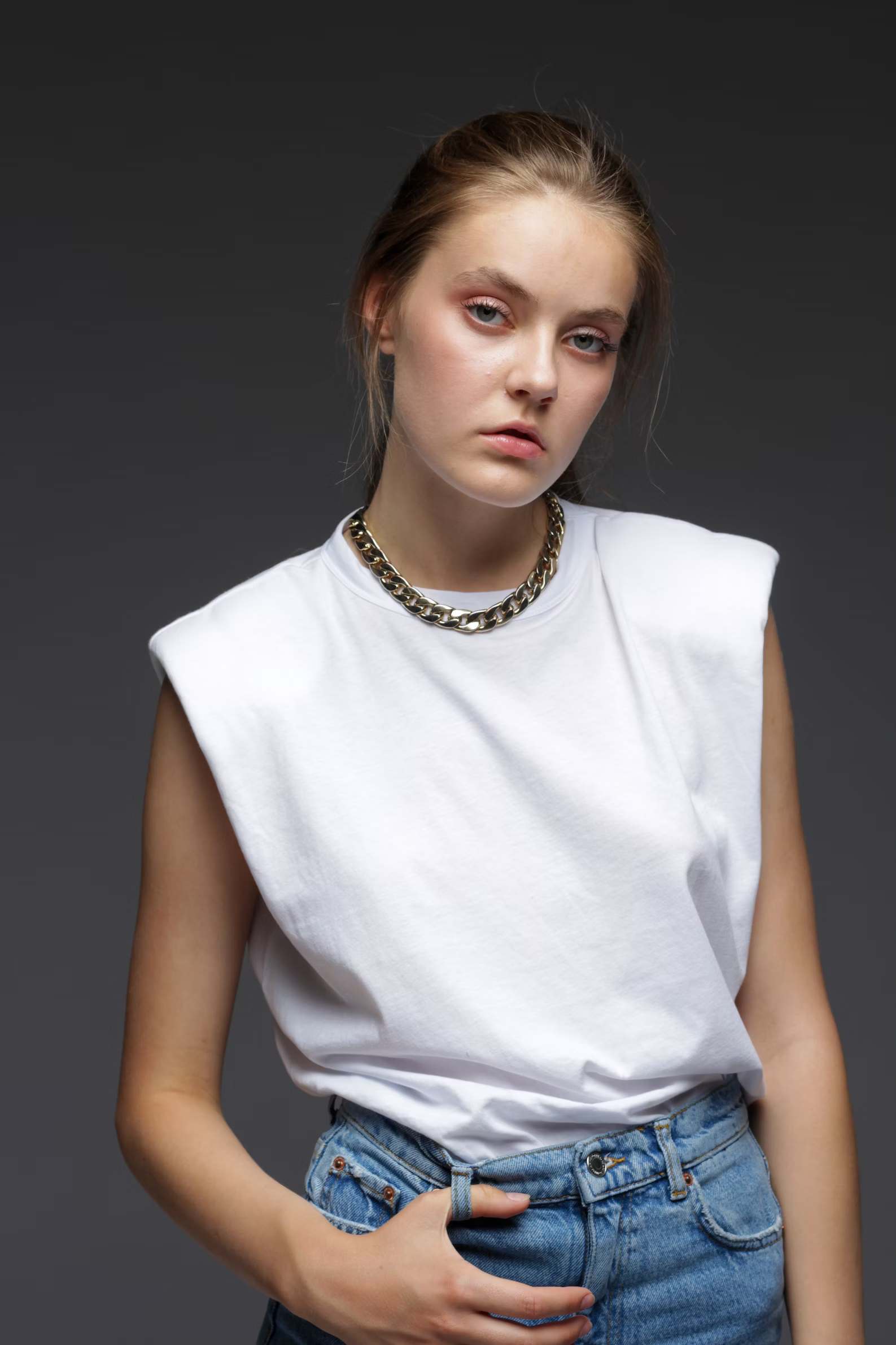 A woman wearing a plain white tee with gold chain