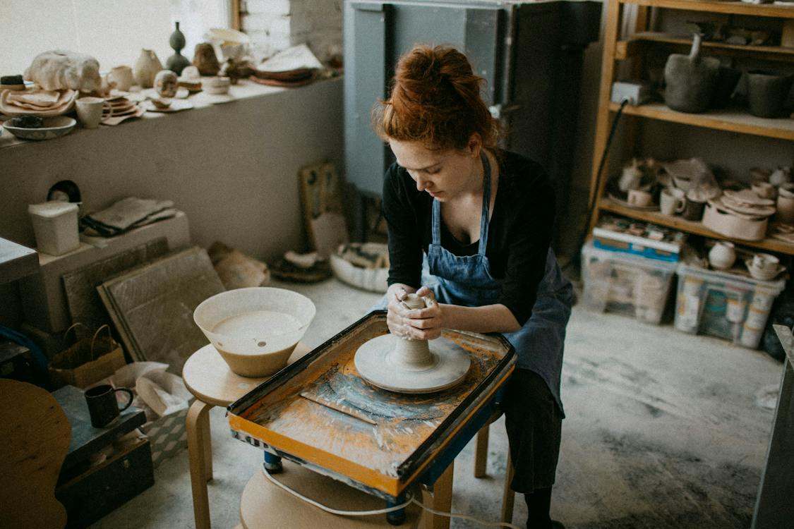 A woman with denim apron doing pottery