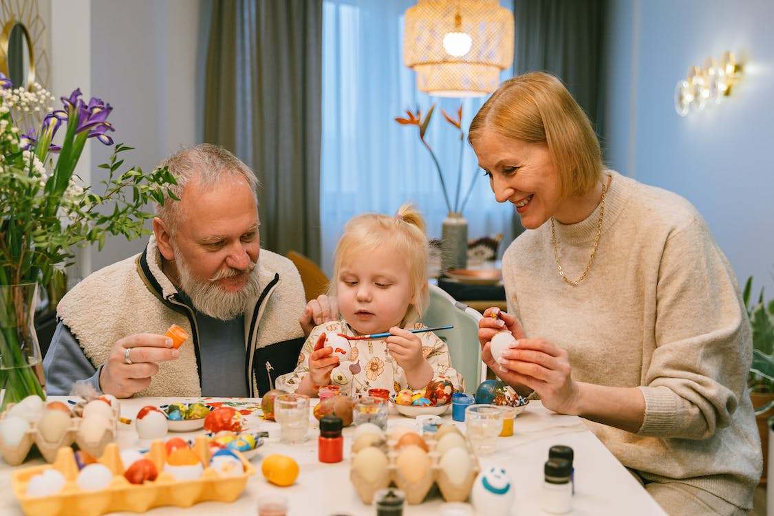 Elderly Couple Painting Easter Eggs with child