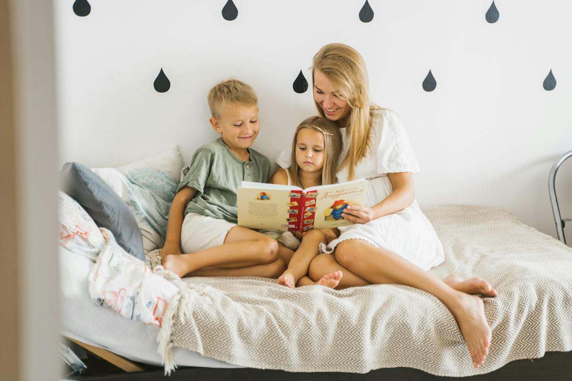 Photograph of a Mother Reading a Book to Her Children