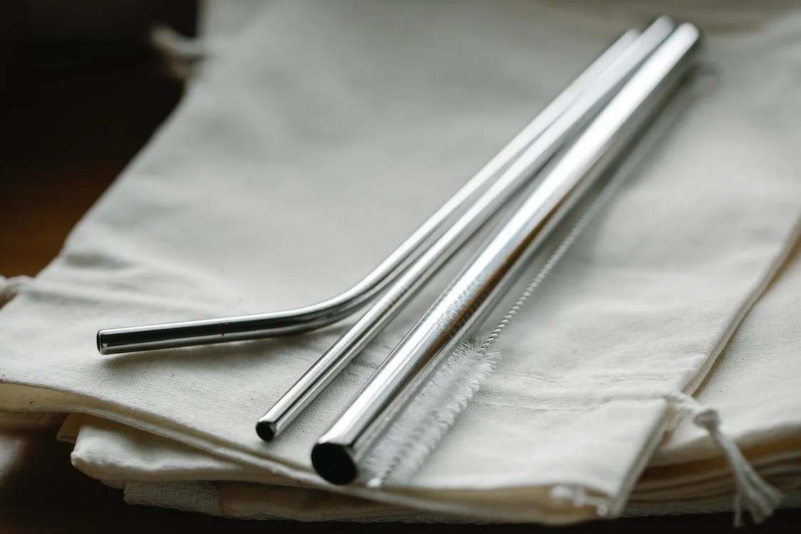 Three metal straws with brush on top of a white cloth