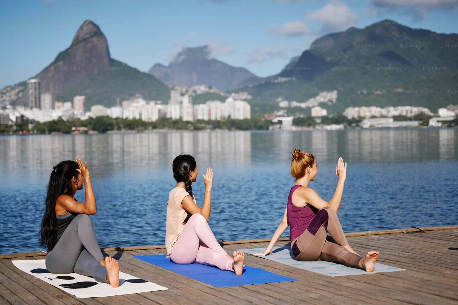 Three women doing yoga seaside